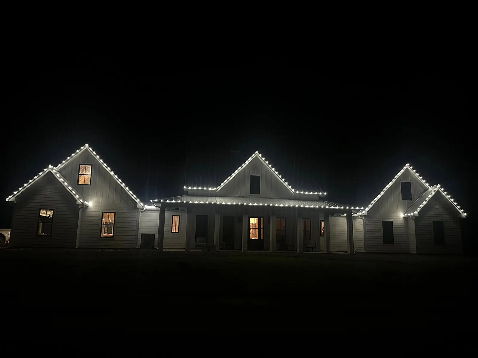 Completed warm-white Christmas lights tracing a residential roofline
