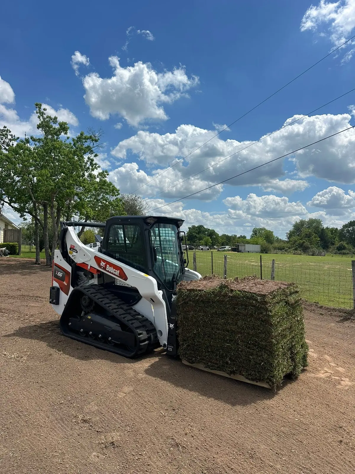 Skid steer transporting a pallet of sod during installation